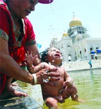 A woman gives a holy dip to her child at the Bangla Saheb Gurdwara in New Delhi on the occasion of Baisakhi on Tuesday. Tribune photo: Manas Ranjan Bhui