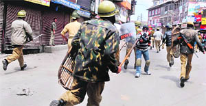 Policemen chase away youths protesting against the conviction of six Kashmiris in the Lajpat Nagar blast, in Srinagar on Tuesday.