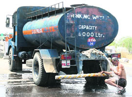 A man takes a bath under a water tanker to beat the heat in Jammu on Wednesday.
