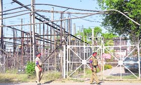 Policemen on vigil outside the locked entry gate of a power station on the GT road in Ludhiana