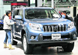 Customers look at a Toyota Land Cruiser Prado at the company's showroom in Tokyo on Thursday. Embattled automaker Toyota suspended worldwide sales of its Lexus GX 460 SUV due to a rollover risk at high speed. Toyota will also start testing all other SUV models, including the Land Cruiser, Land Cruiser Prado and Rav4, the companys spokesperson said.