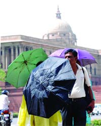 People hide under umbrellas at Vijay Chowk in New Delhi