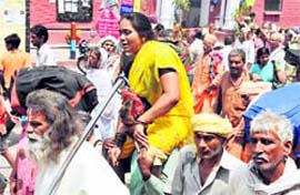 A woman being carried by a man from Har-ki-Pauri to Haridwar railway station on Thursday. A Tribune photograph