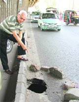 A commuter shows a damaged road stretch in Ludhiana.