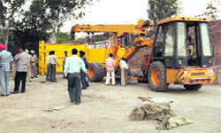 Encroachment by Jaypee Cement near Dehni village at Anandpur Sahib along NH-21 being removed on Thursday.