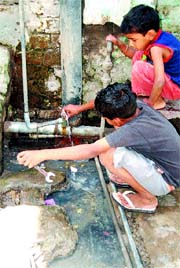 Children try to repair a leaking tap near a open drain in Ward 42. Photo: Vishal Kumar