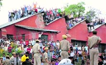 Fans sit atop a building to watch the IPL cricket match between Chennai Super Kings and Kings XI Punjab at Dharamsala on Sunday. 