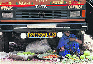 A vendor takes shelter under a truck to shield herself from the scorching sun in New Delhi on Sunday.