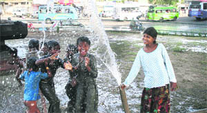 Children try to beat the heat by taking a shower from a water pipe at Dogra Park in Jammu.