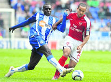 Arsenals Theo Walcott (R) vies with Wigans Steve Gohouri on Sunday.