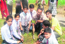 Students from Graphic Era University and Dehradun Hills Academy plant a sapling in Dehradun on Tuesday. 