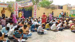 Students sitting on road in front of the Modern Public High School, Guru Har Sahai, to write their practical exam on Wednesday. 