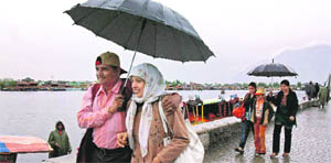 Tourists enjoy themselves in the rain on the banks of the Dal Lake in Srinagar on Wednesday.