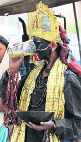 A beggar dressed as a goddess gulps down sugarcane juice to beat the heat in Karnal.