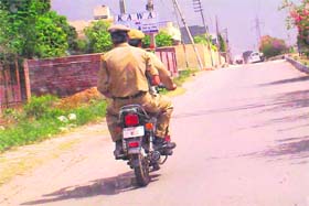 Flouting rules: Two policemen without helmets ride a motorcycle having no number plate at Greater Kailash in Jammu