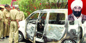 Policemen inspect the car that caught fire, killing R.S. Bhatia (inset), in New Delhi on Friday.