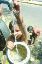 Children take bath on the roadside to beat Delhis heat.