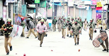 Security forces chase away youths during a protest called by the separatists against the death sentence to three persons by a Delhi court, in Srinagar
