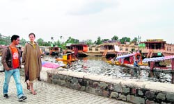 A tourist from New Zealand (right), wearing a Kashmiri pheran, walks on the banks of the Dal Lake in Srinagar