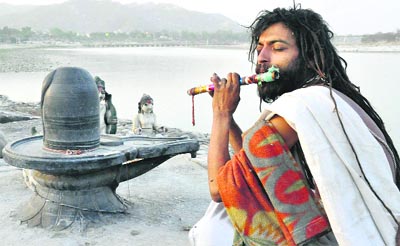 A sadhu plays a flute on the banks of the Ganga in Haridwar 