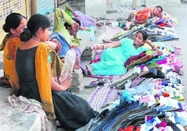 With no customers to attend to, vendors of old clothes while away their time in Karnal.