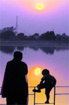 A woman along with a child admires the sunset at the Thermal Lake in Bathinda on Monday. 