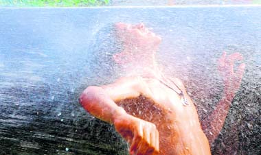 A boy enjoys a shower at a leaking water pipeline near the Chandigarh railway station on a hot Tuesday afternoon. 