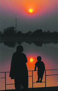 A woman and her son admire the sunset at one of the Thermal lakes in Bathinda.