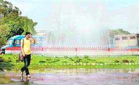 A girl enjoys sprinkles from a fountain in Jammu University