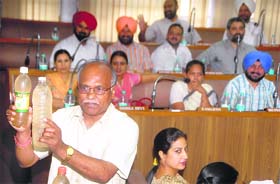 BJP councillor Ram Lal shows bottles containing contaminated water collected from Hallo Majra village during an MC meeting in Chandigarh