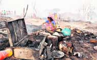 A woman sits beside her goods that were damagad in a massive fire at Hussainpura.