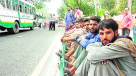 Porters wait for their turn outside the Civil Secretariat in Jammu on Friday to load official records on trucks.