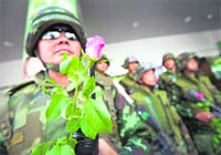A Thai army soldier holds a pink rose given to him by members of Thailands Finance Minister Korn Chatikavanijs entourage as Korn met with security forces, business owners and pedestrians on Silom Road, which was the scene of grenade attacks last week, in Bangkok on Friday.  Reuters
