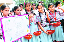 Students carrying earthen pots filled with water for birds gather near the Civil Secretariat on Save Birds Day in Jammu 