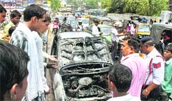 People watch a burnt Maruti Zen, which allegedly caught fire due to a short circuit in Gurgaon on Sunday.