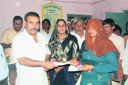 Rao Yadvender Singh hands over cheques to Indira Awas Yojna beneficiaries at Nahar.