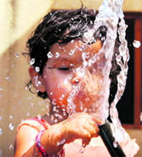 A child plays with water which gushes out from a broken pipeline on the outskirts of Shimla on Monday