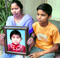 Neelam and Suraj, the mother and brother of Aarti, hold her photograph at their house in Noida