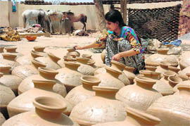 A girl arranges earthenware for drying in the sun at Gharota village in Jammu. 
