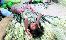 A little broom-maker takes a nap on a hot afternoon in Karnal.