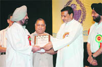 Surgeon Dr Rajinder Singh receives a citation from Health Minister Sham Lal Sharma at the Zorawar Singh Auditorium in Jammu 