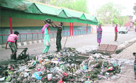 Safai karamcharis of the Jammu Municipal Corporation lift garbage from a choked drain in front of the Civil Secretariat in Jammu