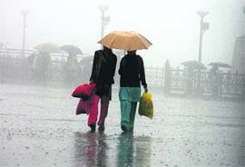 Two girls trying to shield themselves from sudden rain and storm at Shimla on Friday.