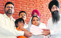 Santosh, wife of the tea vendor, being handed over cheques in Ludhiana