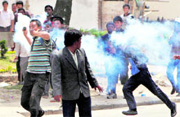 A Maoist activist runs with a tear gas canister towards the Nepalese police during a demonstration in Kathmandu on Sunday