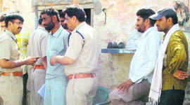 Police officials outside the house where three murders took place in Khokri village. 