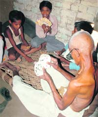 KEEPING THEM TOGETHER, KEEPING THEM IN: An elderly man plays cards with his grandchildren at his house in Mohammadwas village, Nuh (Mewat) on a hot summer afternoon