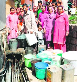 People wait to collect water at Sakoh village near Dharamsala on Sunday.