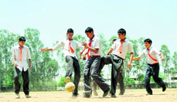Schoolchildren play football during recess in Ludhiana on Monday