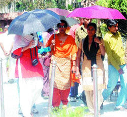Tourists use umbrellas to protect themselves from the scorching heat at Jallianwala Bagh in Amritsar